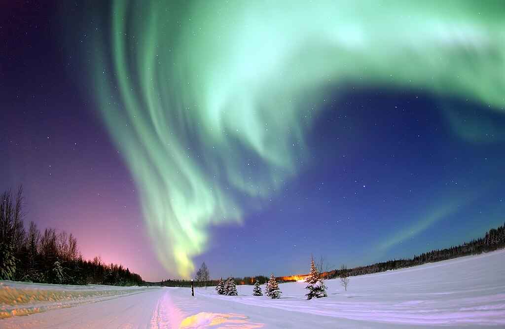 Aurora boreal no círculo polar, com luzes verdes e violetas no céu noturno
