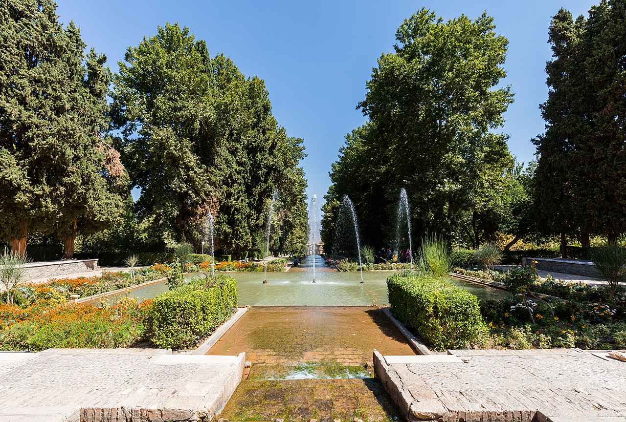 Vista panorâmica do Jardim Shazdeh com fontes e árvores alinhadas em meio ao deserto.